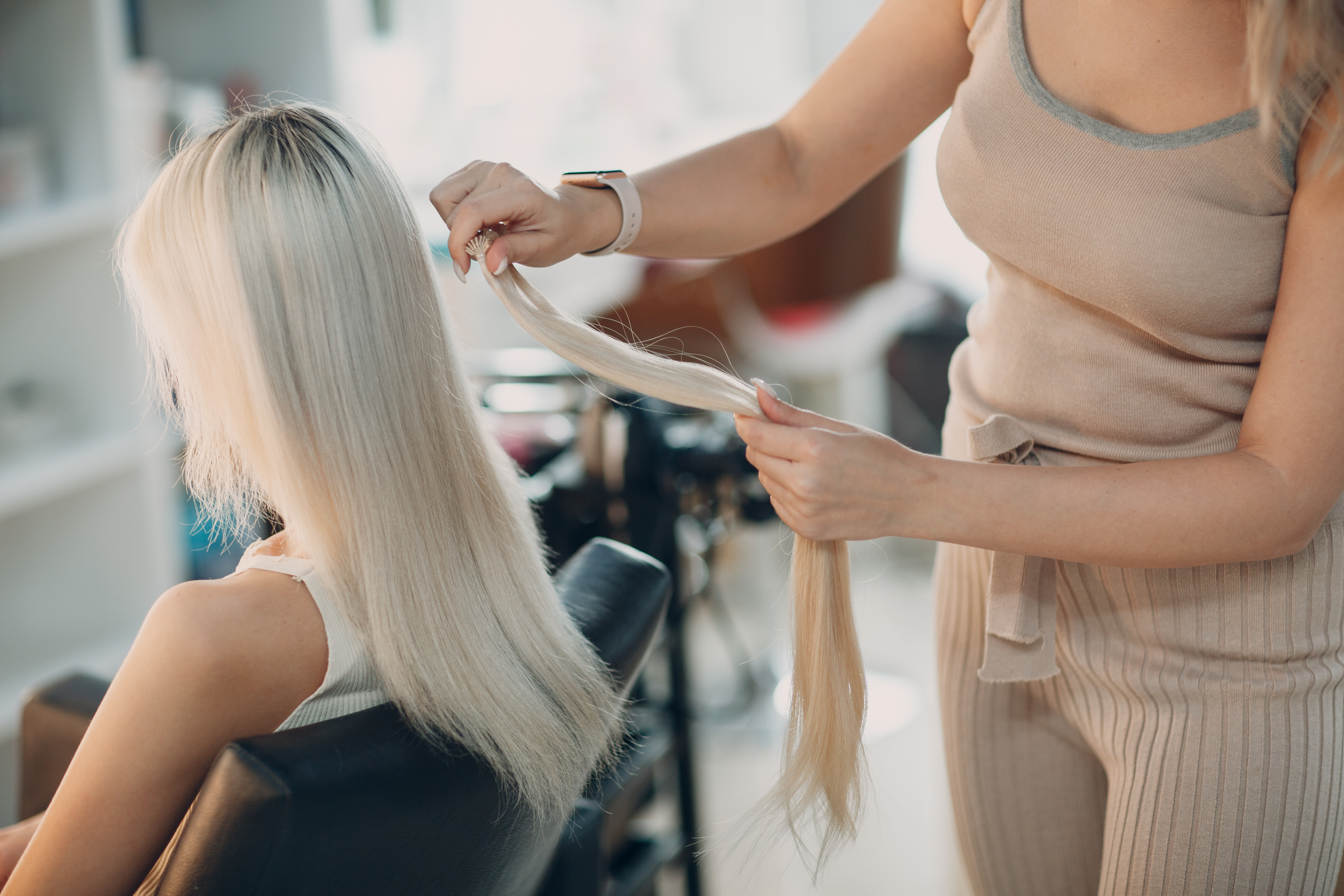 Hairdresser Female Making Hair Extensions to Young Woman with Blonde Hair in Beauty Salon. Professional Hair Extension.
